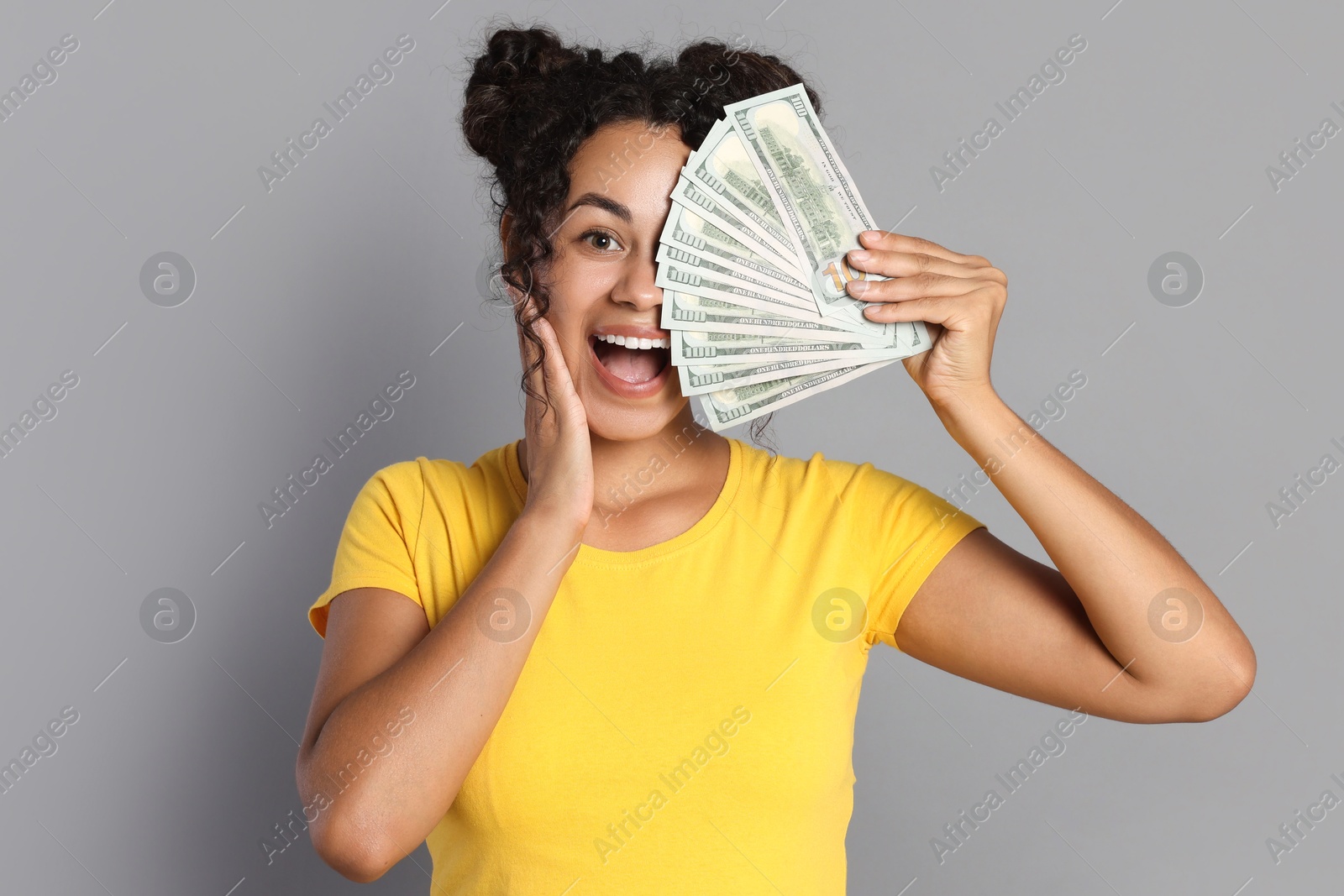 Photo of Happy woman with dollar banknotes on grey background