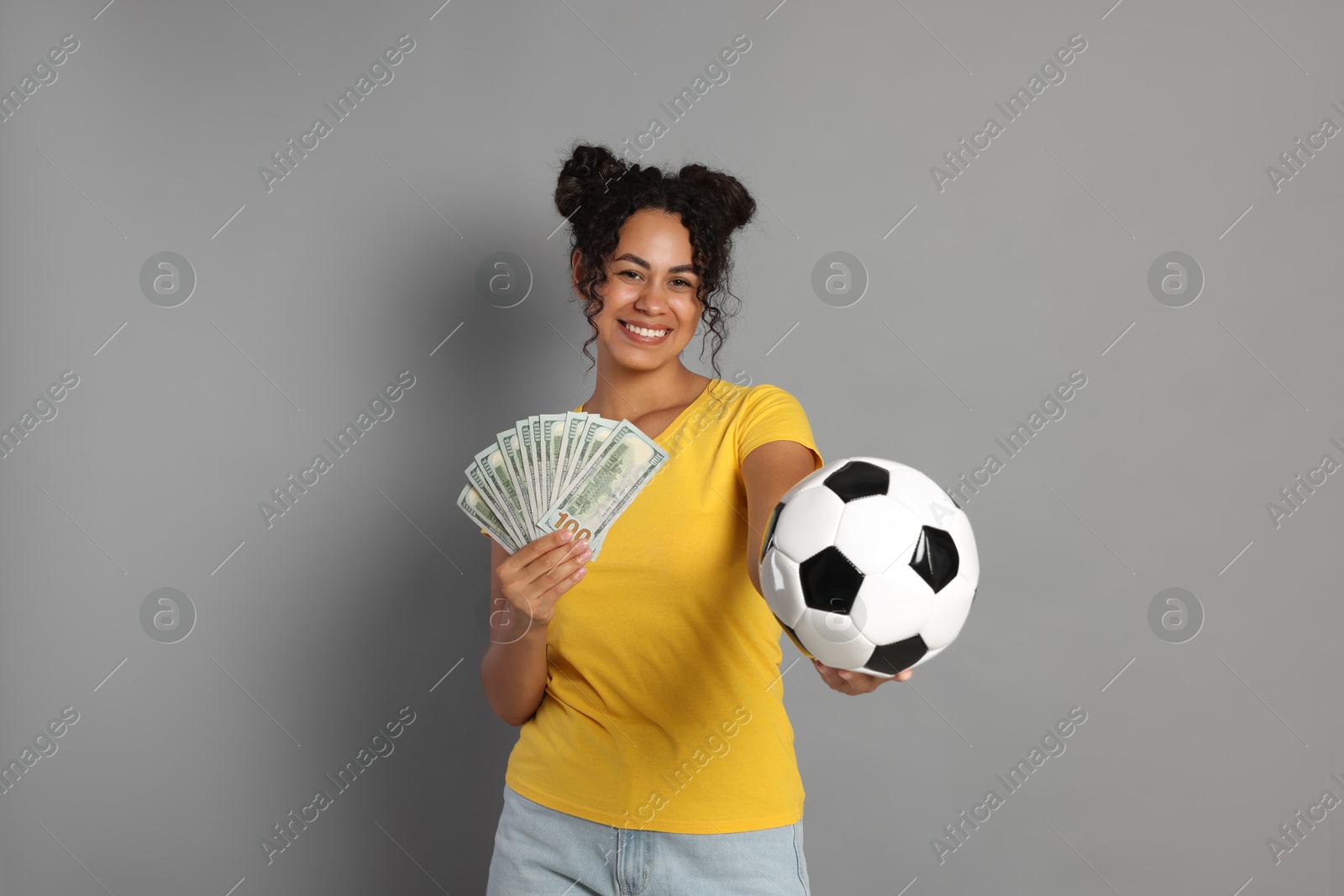 Photo of Happy woman with money and soccer ball on grey background