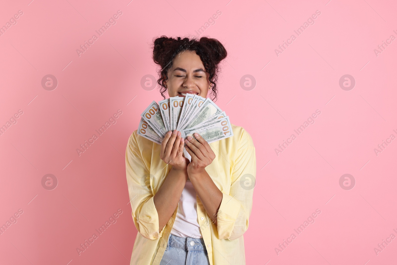 Photo of Happy woman with dollar banknotes on pink background