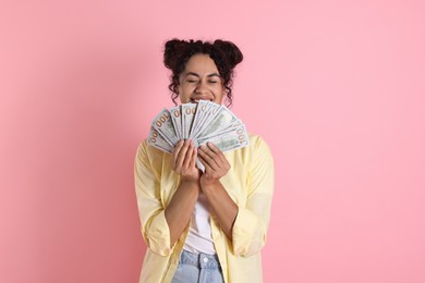 Happy woman with dollar banknotes on pink background