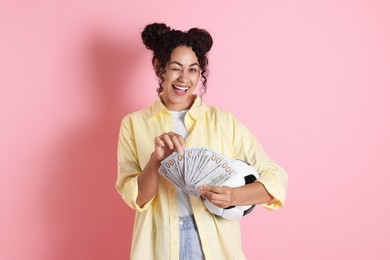 Happy woman with money and soccer ball on pink background