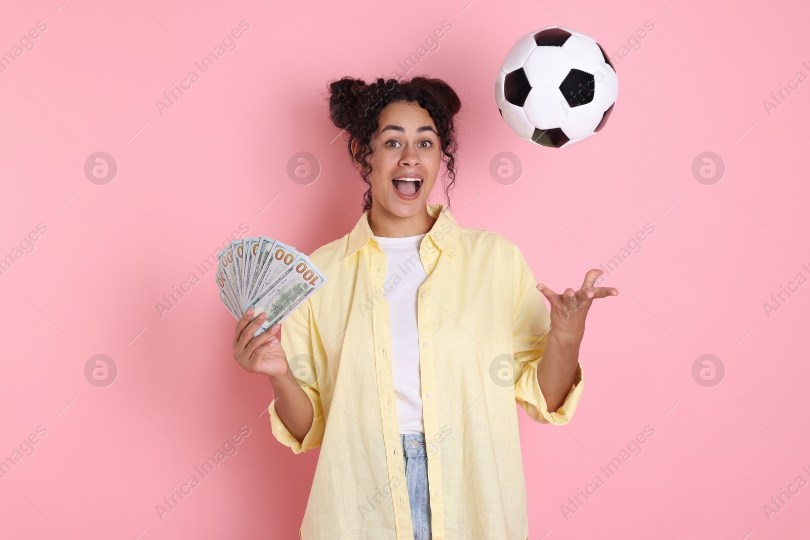 Photo of Happy woman with money throwing soccer ball on pink background