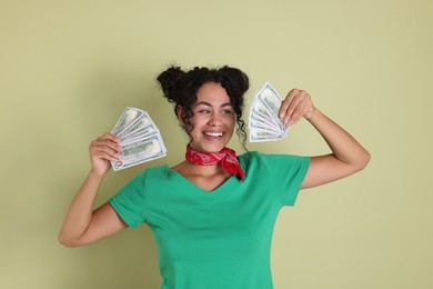 Photo of Happy woman with dollar banknotes on pale green background