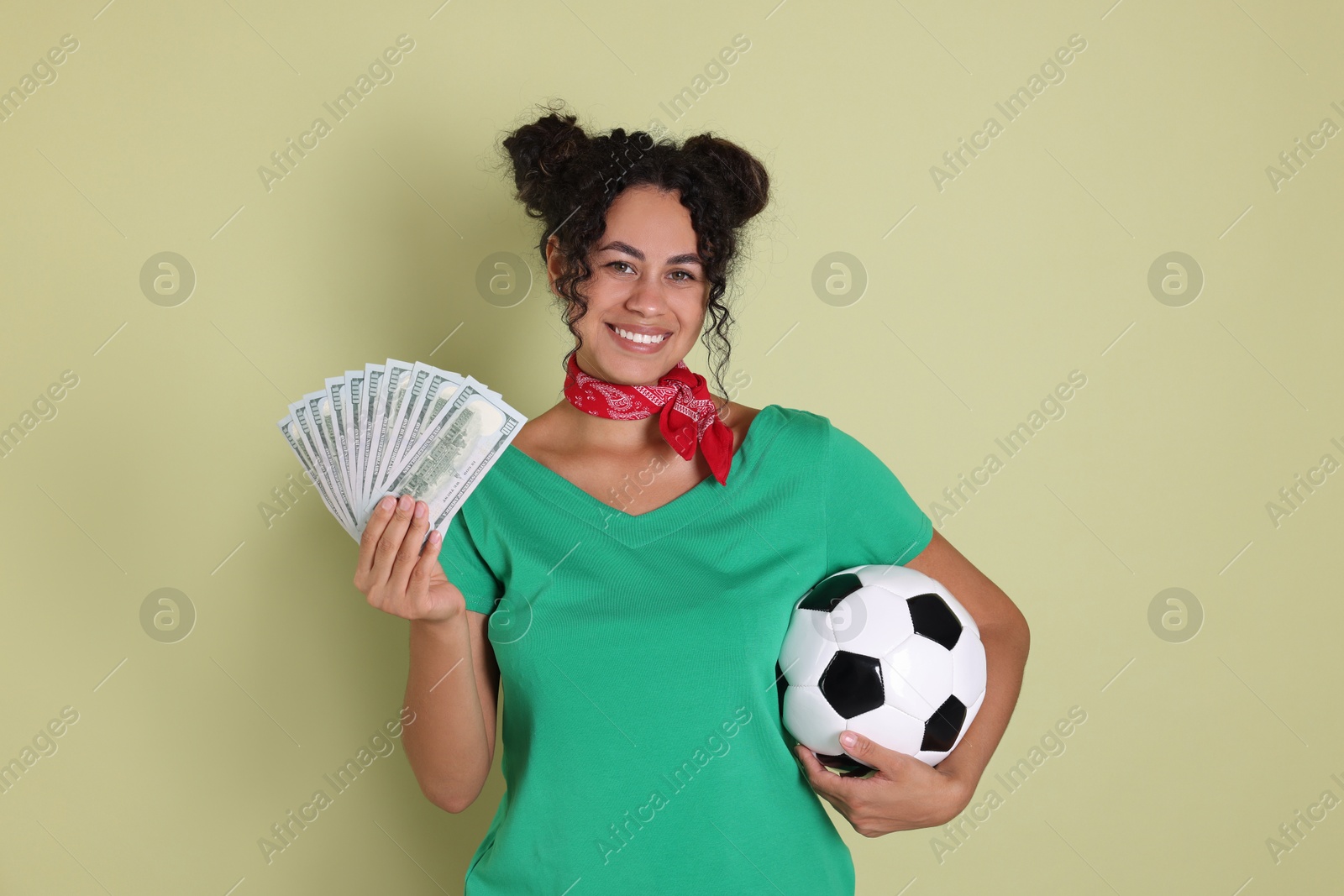 Photo of Happy woman with money and soccer ball on pale green background