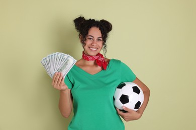 Photo of Happy woman with money and soccer ball on pale green background