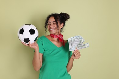 Happy woman with money and soccer ball on pale green background