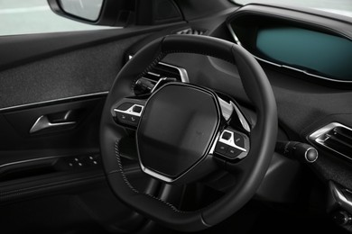 Photo of Steering wheel and dashboard inside of modern luxury car, closeup