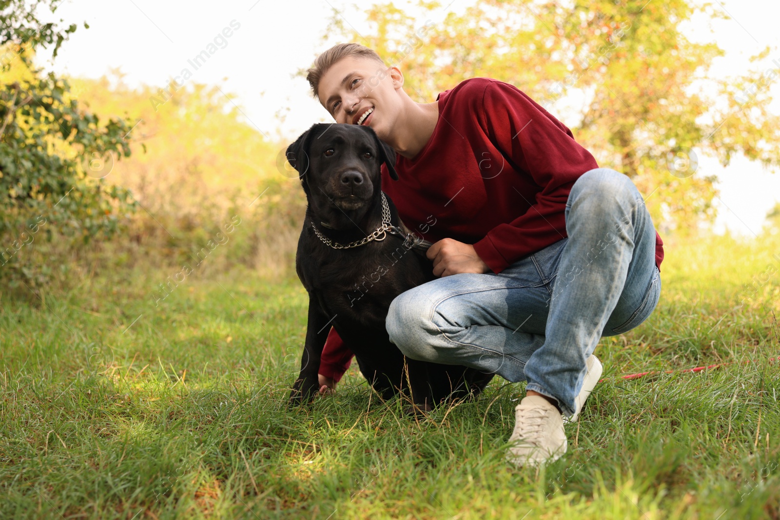 Photo of Smiling man with cute dog outdoors on autumn day. Space for text