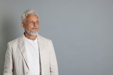 Portrait of senior man on grey background, space for text