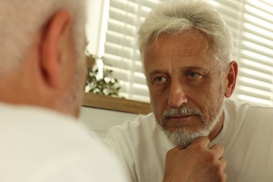 Senior man looking in mirror at home