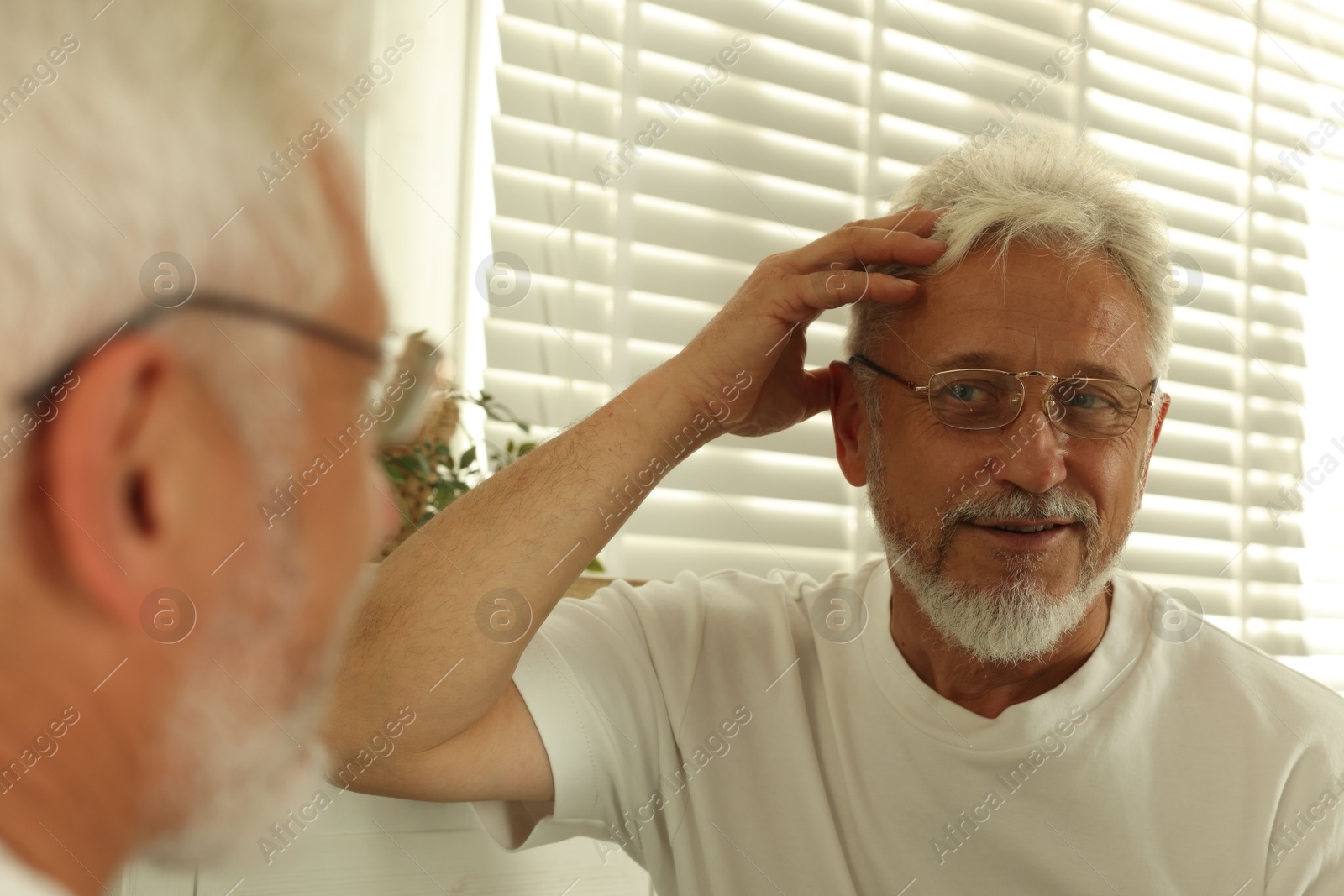 Photo of Senior man looking in mirror at home