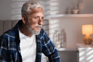 Portrait of senior man with grey hair at home, space for text