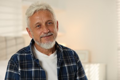 Portrait of senior man with grey hair at home, space for text