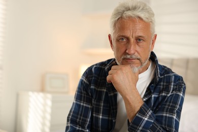 Portrait of senior man with grey hair at home, space for text