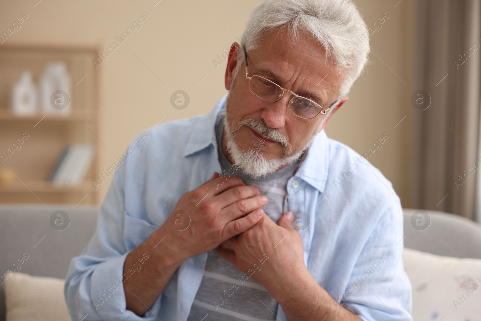 Photo of Senior man suffering from pain in chest at home