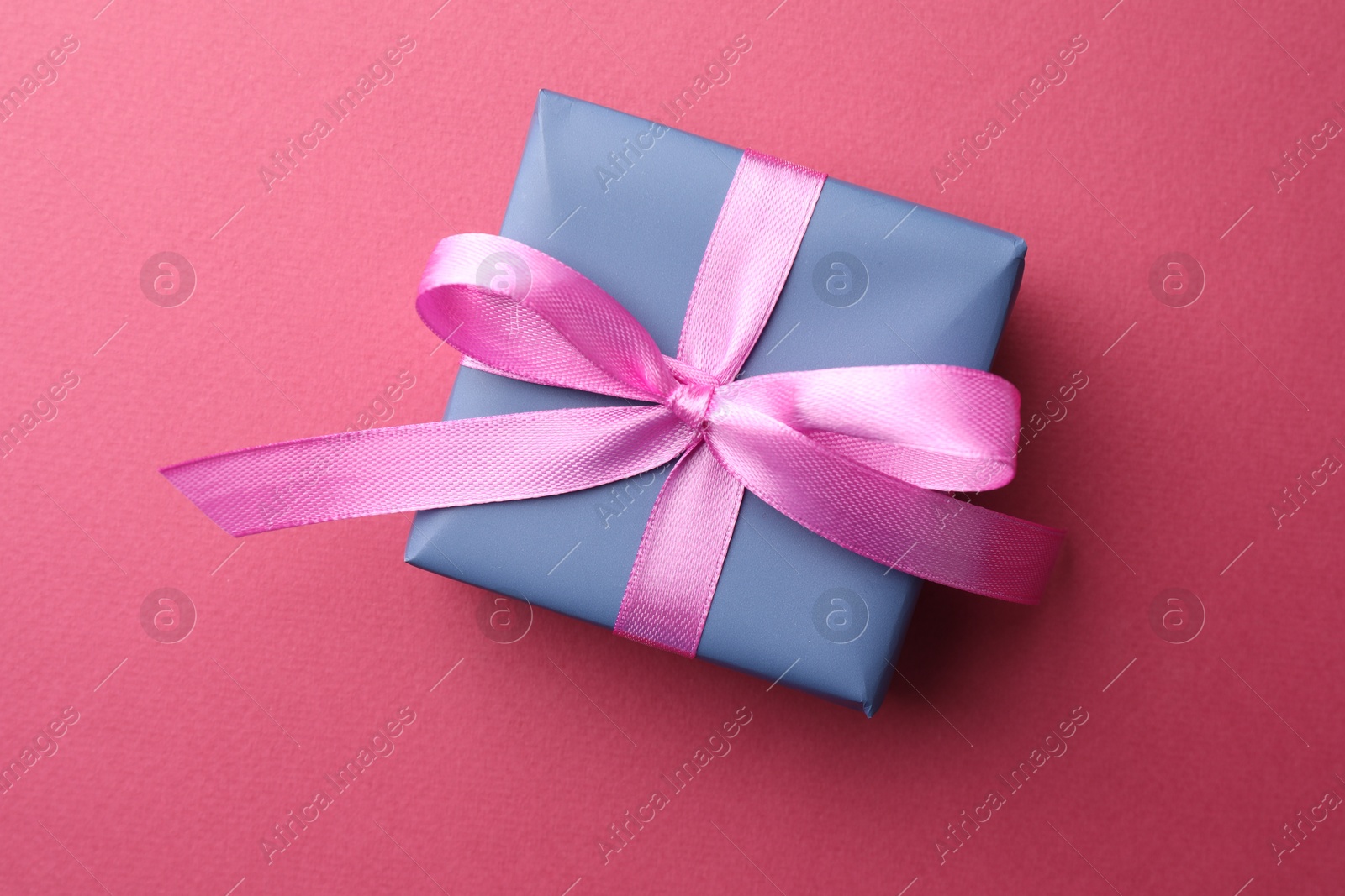 Photo of Beautiful gift box with bow on pink background, top view