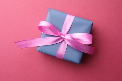 Beautiful gift box with bow on pink background, top view