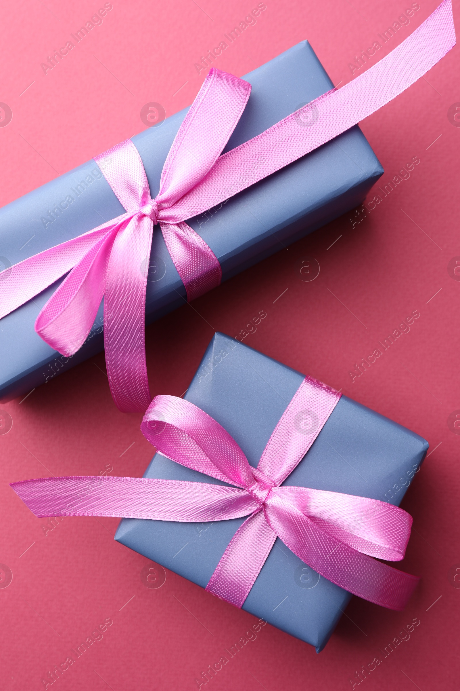 Photo of Beautiful gift boxes with bows on pink background, top view