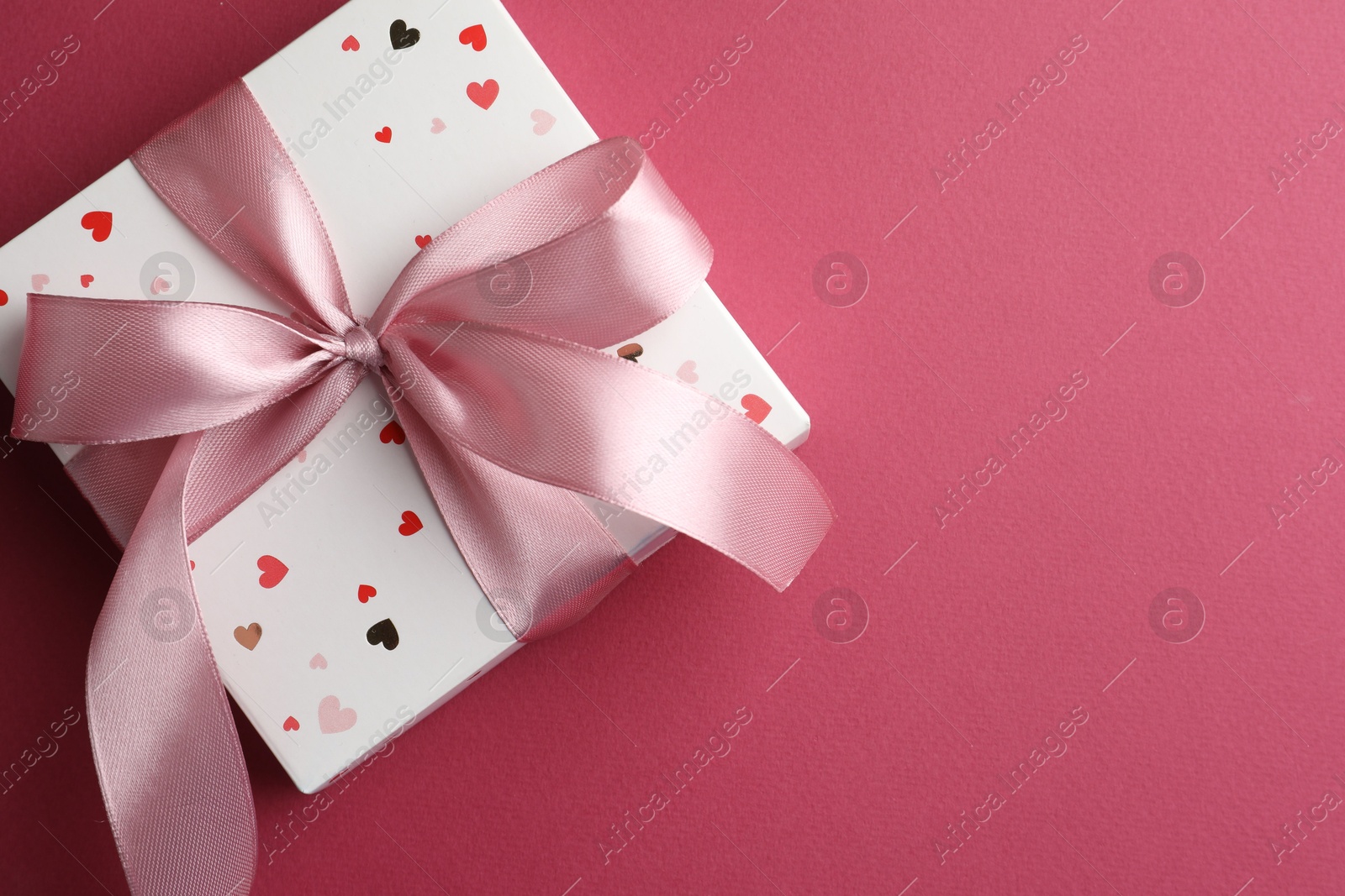 Photo of Beautiful gift box with bow on pink background, top view. Space for text