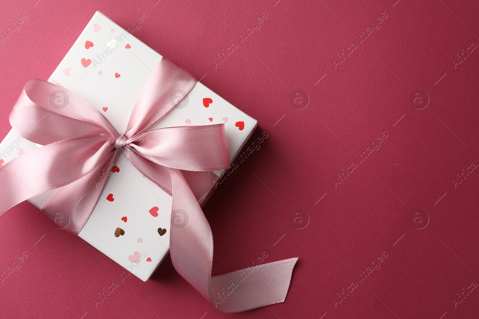 Photo of Beautiful gift box with bow on pink background, top view. Space for text