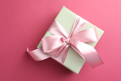 Photo of Beautiful gift box with bow on pink background, top view