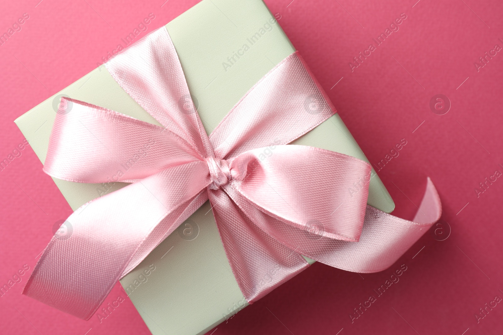 Photo of Beautiful gift box with bow on pink background, top view