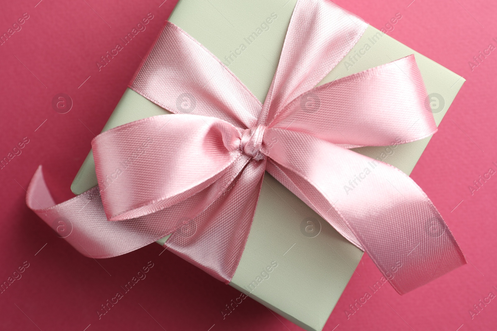 Photo of Beautiful gift box with bow on pink background, top view