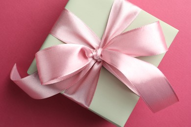 Photo of Beautiful gift box with bow on pink background, top view