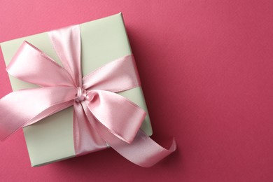 Photo of Beautiful gift box with bow on pink background, top view. Space for text