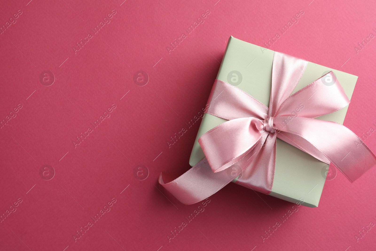 Photo of Beautiful gift box with bow on pink background, top view. Space for text