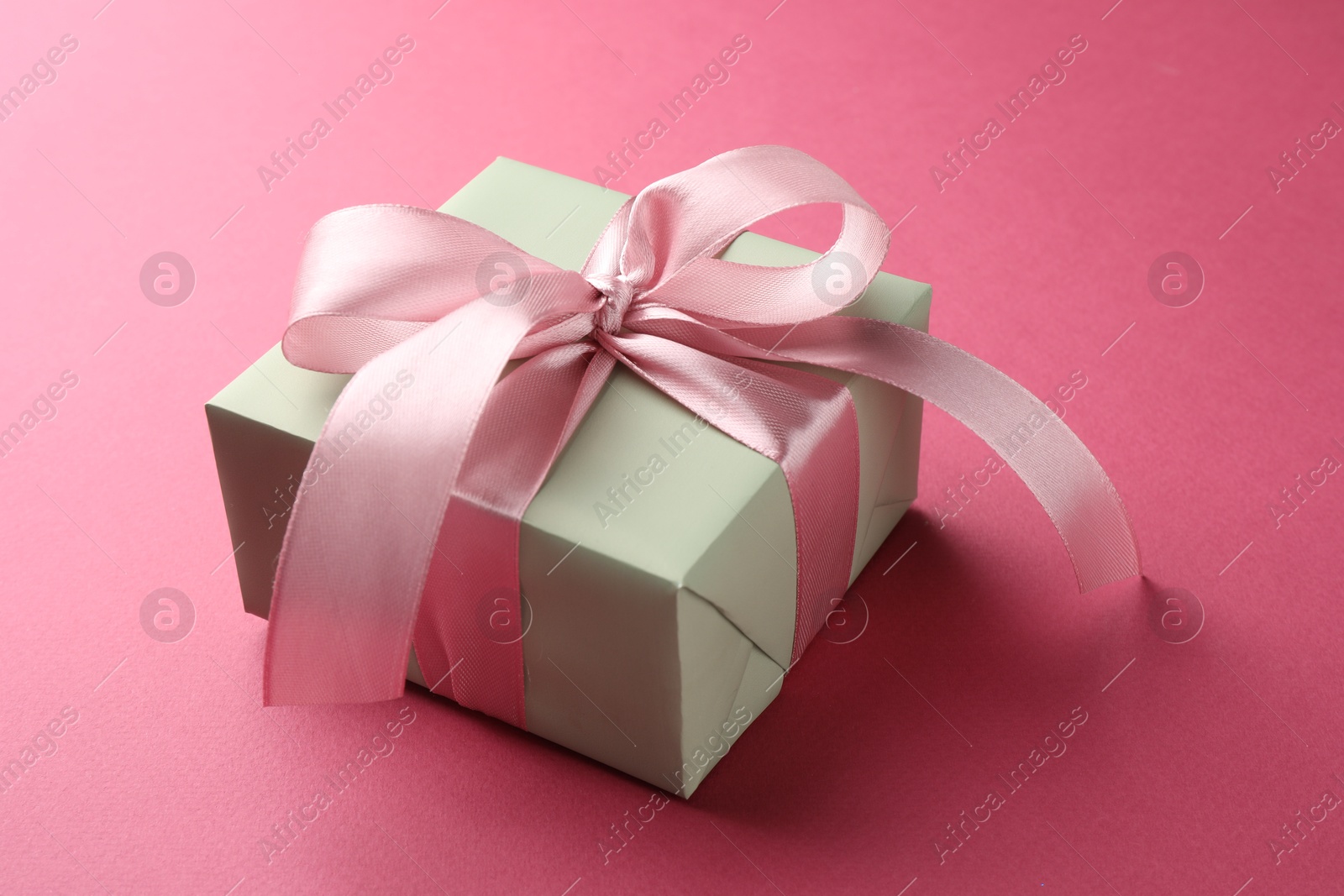 Photo of Beautiful gift box with bow on pink background, closeup