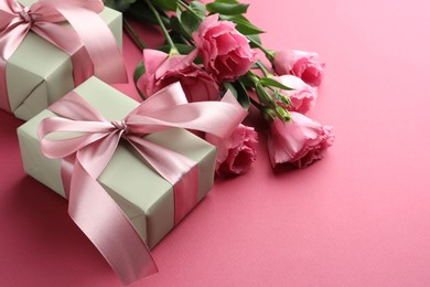 Photo of Beautiful gift boxes with bows and eustoma flowers on pink background