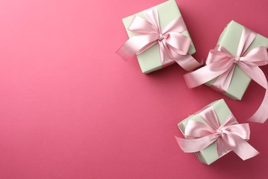 Beautiful gift boxes with bows on pink background, flat lay. Space for text