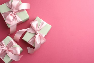 Beautiful gift boxes with bows on pink background, flat lay. Space for text