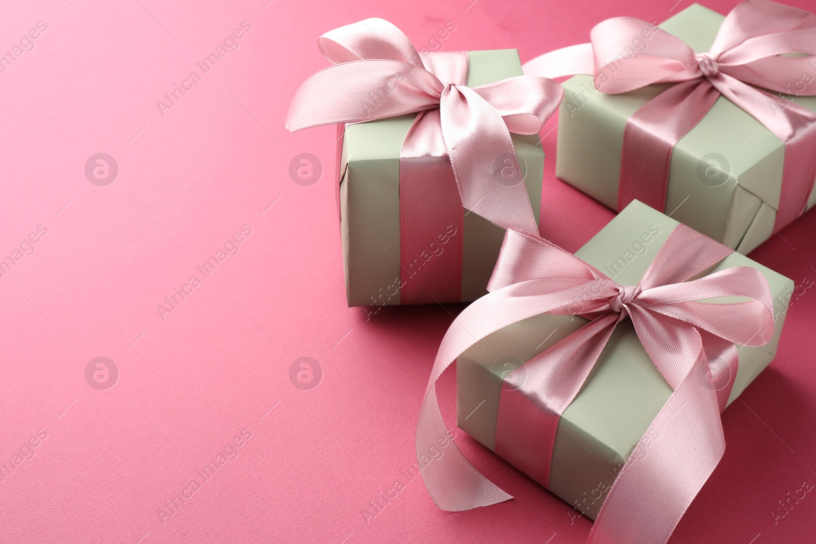 Photo of Beautiful gift boxes with bows on pink background, space for text