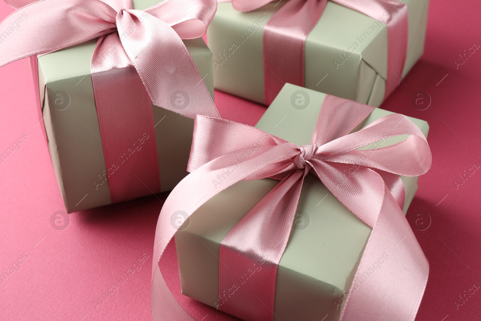 Photo of Beautiful gift boxes with bows on pink background, closeup