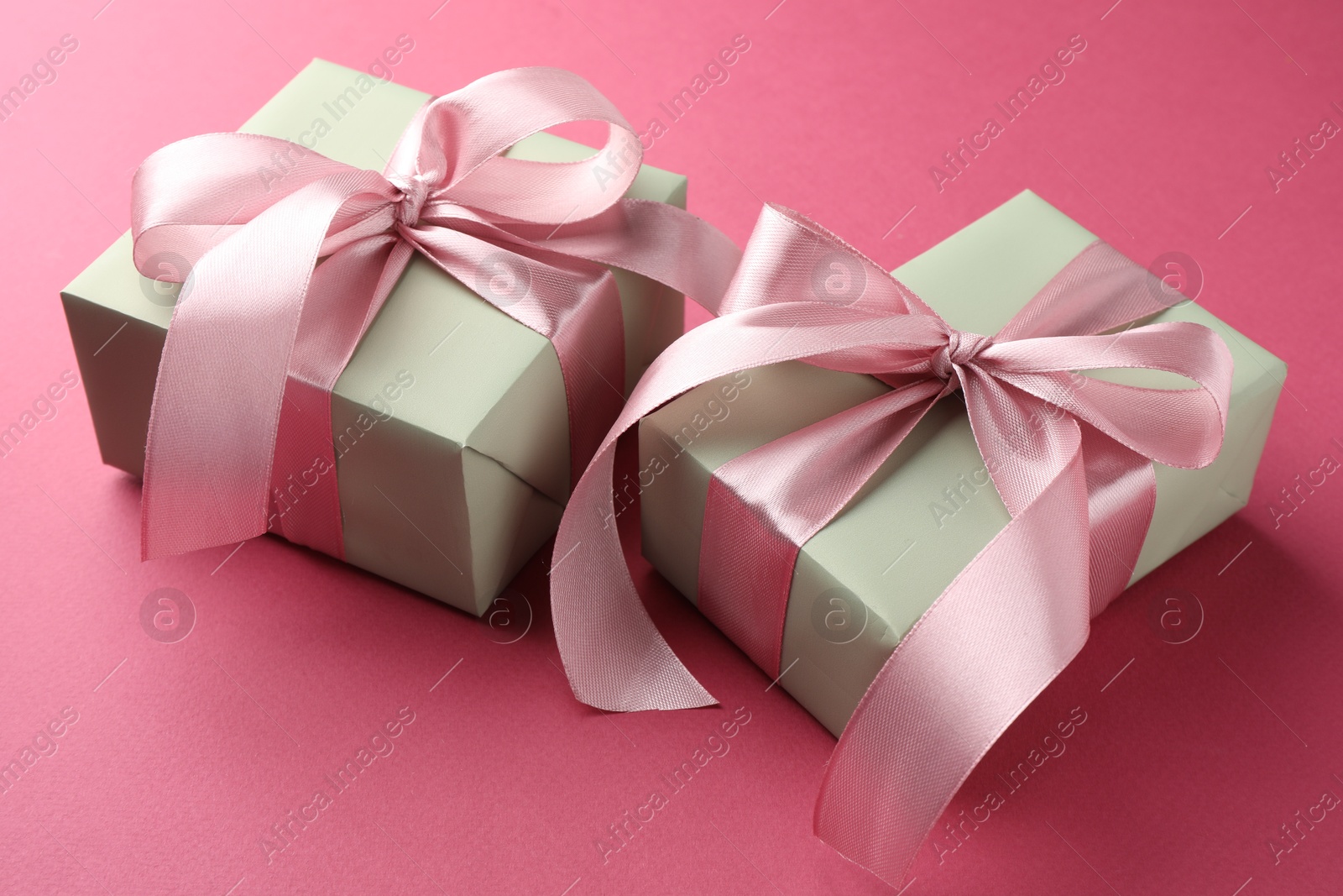 Photo of Beautiful gift boxes with bows on pink background