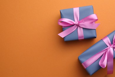 Photo of Beautiful gift boxes with pink bows on orange background, top view. Space for text