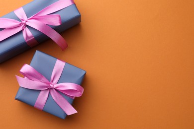 Photo of Beautiful gift boxes with pink bows on orange background, top view. Space for text