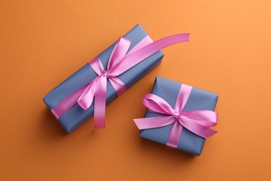 Photo of Beautiful gift boxes with pink bows on orange background, top view