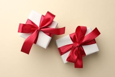 Beautiful gift boxes with red bows on beige background, top view