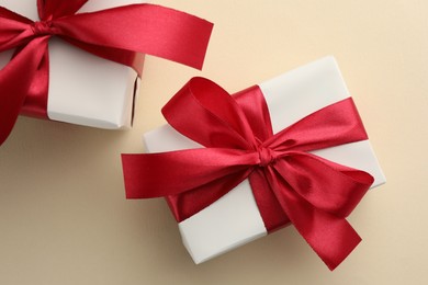 Photo of Beautiful gift boxes with red bows on beige background, top view