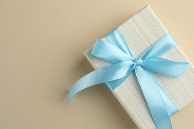 Beautiful gift box with light blue bow on beige background, top view. Space for text