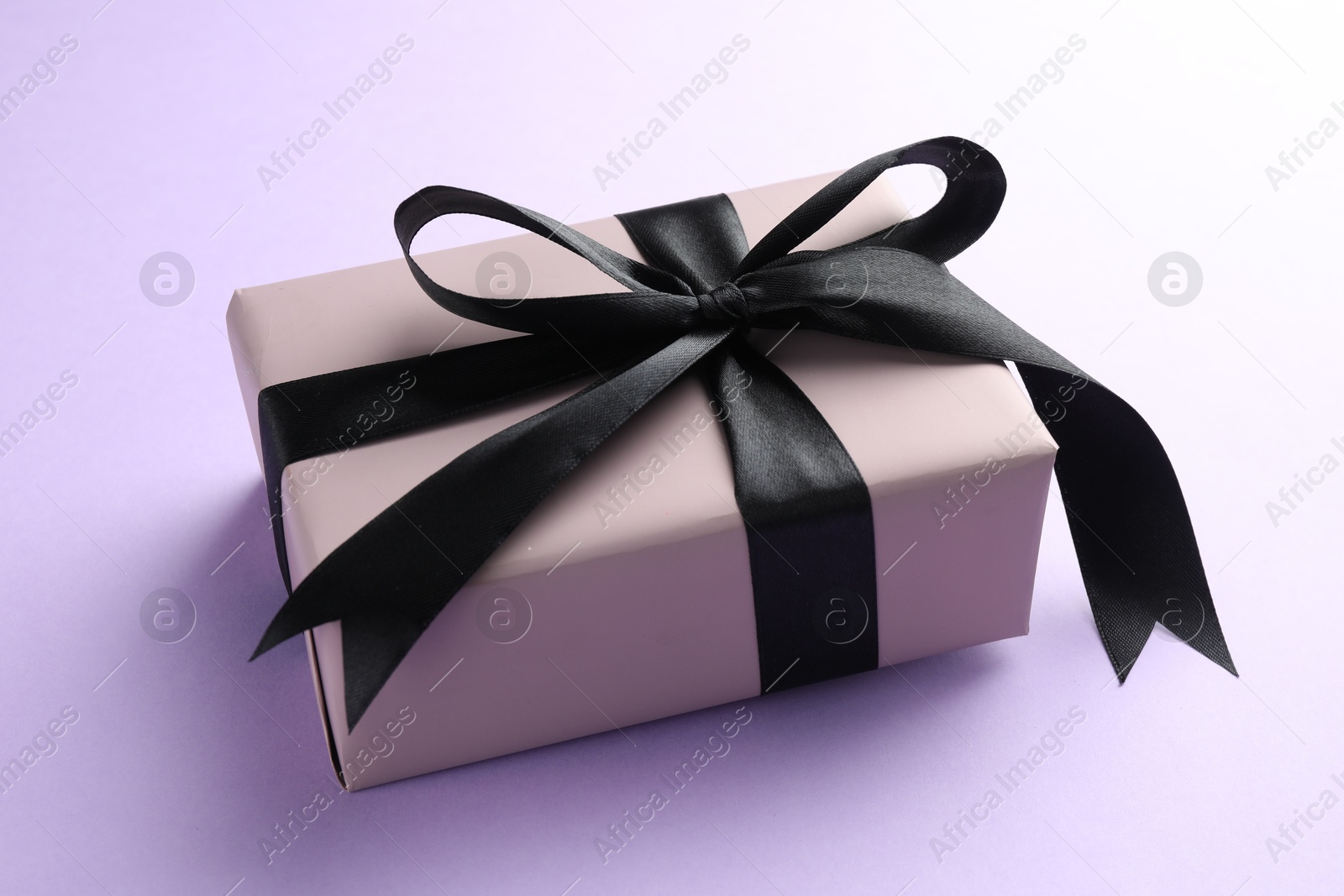 Photo of Beautiful gift box with black bow on violet background