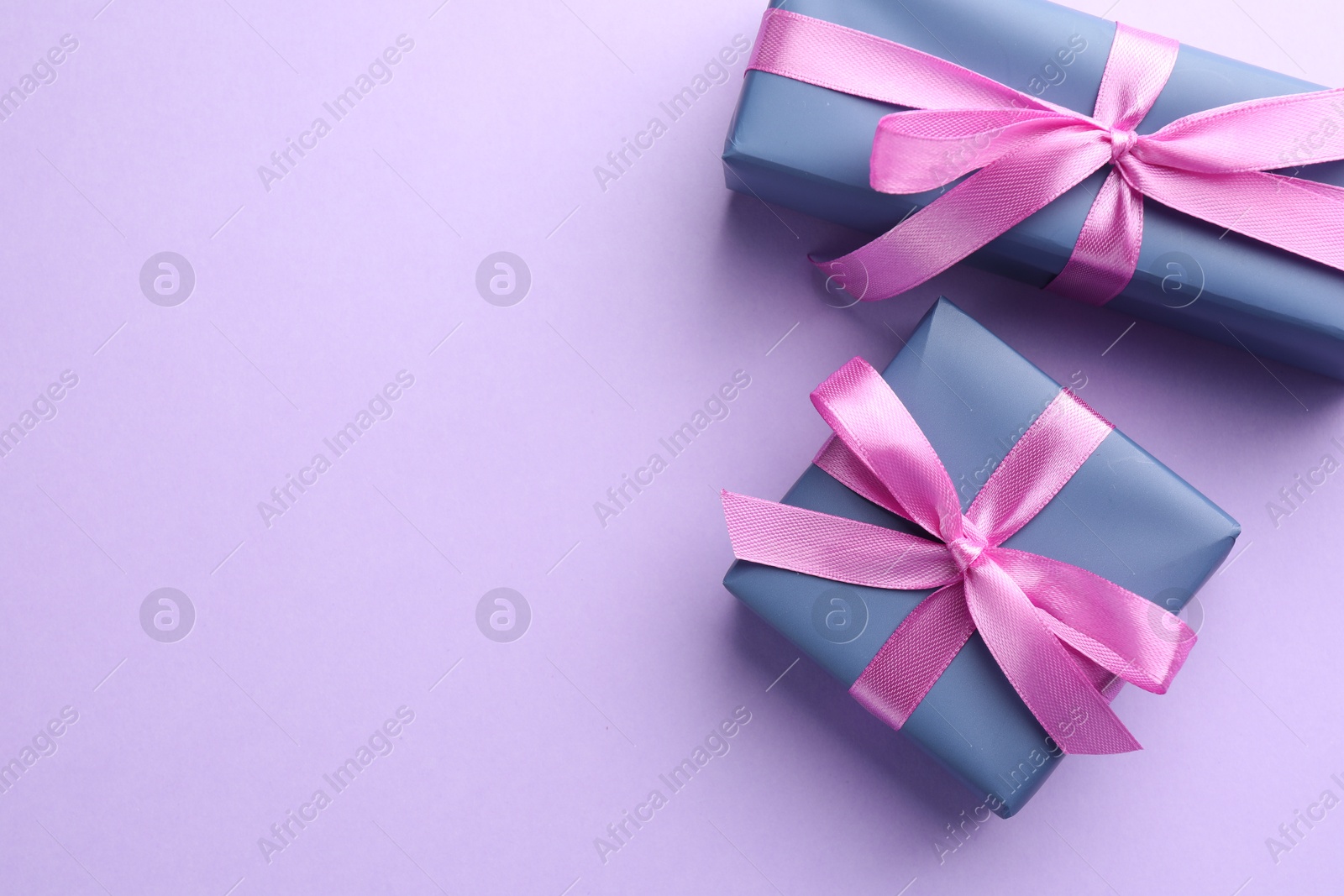 Photo of Beautiful gift boxes with pink bows on violet background, top view. Space for text