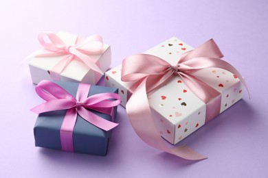 Beautiful gift boxes with pink bows on violet background