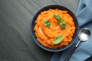 Photo of Tasty mashed sweet potato in bowl served on dark gray textured table, flat lay