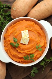 Photo of Tasty mashed sweet potato with butter in bowl, fresh vegetables and parsley on table, flat lay