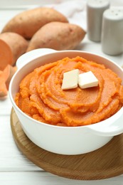 Photo of Tasty mashed sweet potato with butter in bowl on white wooden table, closeup