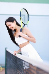 Beautiful woman with tennis racket on court